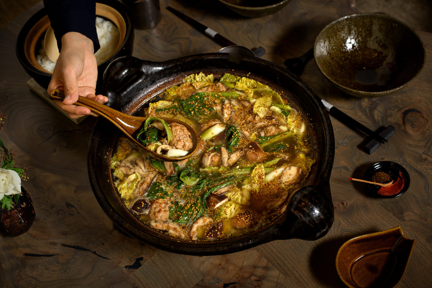 Hand spooning out a serving from the donabe pot